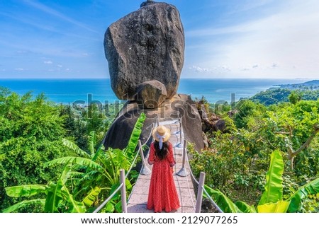 Asian woman tourist in red dress sightseeing and enjoying the view of overlap stone at Koh Samui in Thailand Royalty-Free Stock Photo #2129077265