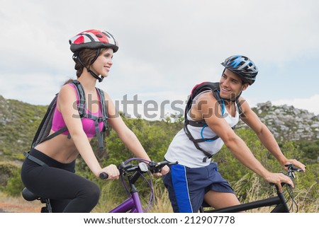 Side view of an athletic couple mountain biking