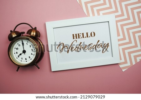 Hello Wednesday and Alarm clock on pink background