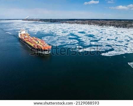 Aerial view of a container ship going upstream through winter ice in the St. Lawrence River near the port of Montreal in Canada Royalty-Free Stock Photo #2129088593