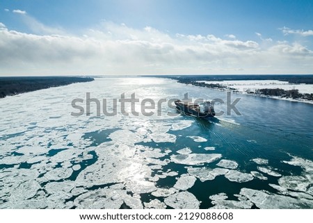 Aerial view of a container ship going upstream through winter ice in the St. Lawrence River near the port of Montreal in Canada Royalty-Free Stock Photo #2129088608