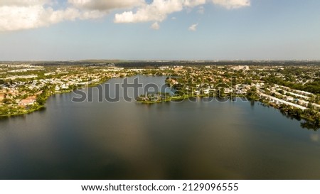 A high angle, aerial shot which was taken with a drone high over Margate, Florida on a beautiful day. Shot over a residential neighborhood with the sky and white clouds reflecting on the water. Royalty-Free Stock Photo #2129096555