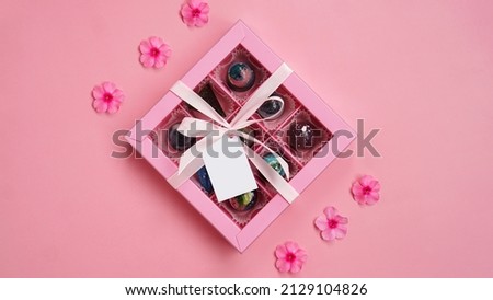 Chocolate candy. Pink gift box with handmade chocolates on a pink background. Festive background. White tag. Mockup