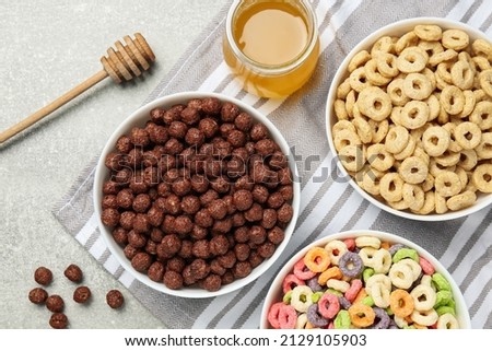 Different delicious breakfast cereals and honey on light grey table, flat lay Royalty-Free Stock Photo #2129105903