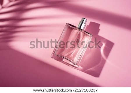 Transparent bottle of perfume on a pink background. Fragrance presentation with daylight. Trending concept in natural materials with window shadow. Women's essence. Royalty-Free Stock Photo #2129108237