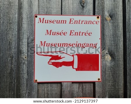 A sign telling people where the museum entrance is. There is a hand with a finger pointing in the direction of the front entrance.