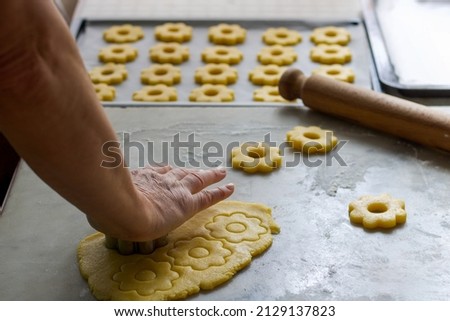 female hand cutting biscuits from the dough in flower shape Royalty-Free Stock Photo #2129137823