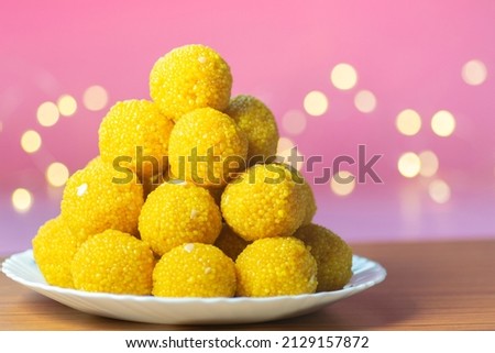 Laddu sweet stacked in white ceramic plate with pink background and yellow bokeh. Bundi Laddu made during many festivals in India specially in hindu festivals and also during marriage ceremony. Royalty-Free Stock Photo #2129157872