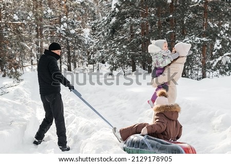 cheerful family on a weekend rides a sleigh in a snowy forest. High quality photo
