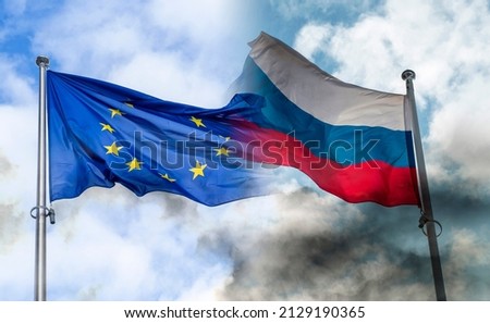 Russian and EU flags covered by black smoke, concept picture about sanctions and conflicts Royalty-Free Stock Photo #2129190365