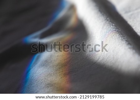 Beam of sunlight with spectrum colors goes over white fabric, physical refraction effect. Abstract close up photo background