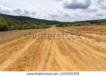 Clearing, grading, leveling and clearing of vegetation on land field for the construction of road or highway Royalty-Free Stock Photo #2129205398