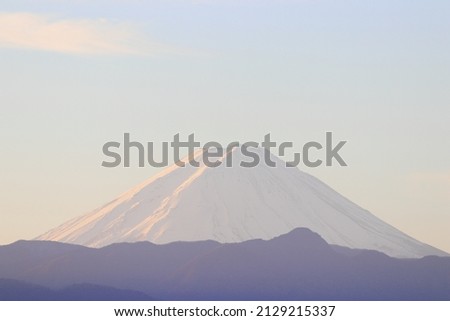 World heritage Mt. Fuji in Japan, the morning sun reflects on the snow, and the pink mountains, clouds and sky are very beautiful.
