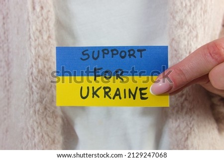Woman holding Ukrainian flag with text support for Ukraine. Military aggression concept