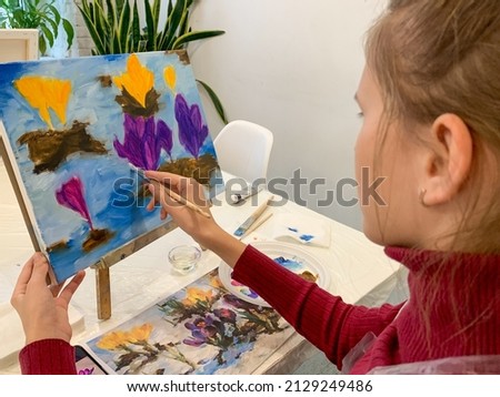 girl paints an oil painting on canvas. young artist workplace art