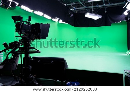 The camera on the tripod, led floodlight, spotlight, prompter and a monitor on a green background. The chroma key. Green screen. Broadcast industry