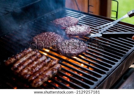 Smoky hamburger meat grilling for burgers. Fry on an open fire on the grill - bbq.Burgers and sausages Cooking Over Flames On The Grill.