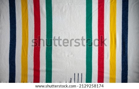 Detail of a bay blanket with green, red, yellow and blue stripes.