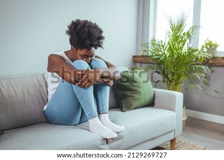 Unhappy lonely depressed woman at home, she is sitting on the couch and hiding her face on a pillow, depression concept. Psychology, solitude and people Royalty-Free Stock Photo #2129269727