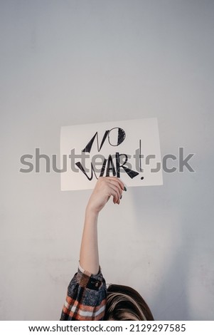 No war protest poster on white sheet, female hands. High quality photo