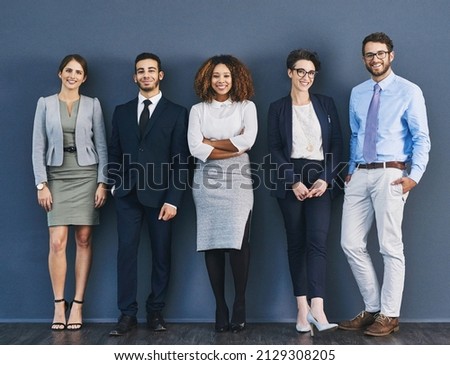 Surrounded by business minded individuals. Studio shot of a group of businesspeople standing in line against a gray background. Royalty-Free Stock Photo #2129308205