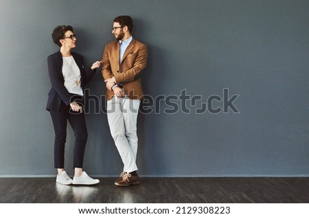 You gain so much from mingling. Shot of two designers having a conversation while leaning against a wall. Royalty-Free Stock Photo #2129308223