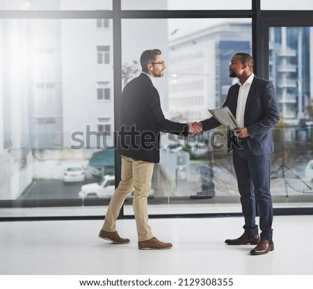 Combining corporate talent. Shot of two businessmen shaking hands at work. Royalty-Free Stock Photo #2129308355