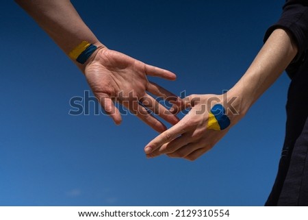 female hands painted in Ukraine flag colors yellow-blue. Stop the war and the power of Ukraine, patriotism and Kiev, strength and power Royalty-Free Stock Photo #2129310554