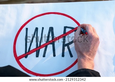 the male hand of an obviously elderly man constructs a poster on the theme against the war to express his protest