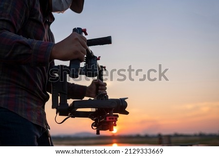 Filmmaker or content creator using stabilizer gimbal camera take video footage on the location outdoor Royalty-Free Stock Photo #2129333669