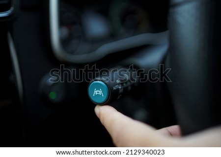 Unrecognizable man driver activating the adaptive cruise control or steering assistant on the control stick behind steering wheel  in electric vehicle - EV. Driving Assist system in modern car. Royalty-Free Stock Photo #2129340023