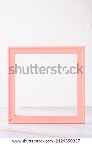 pastel pink picture frame with olive leaf on marble table with concrete wall