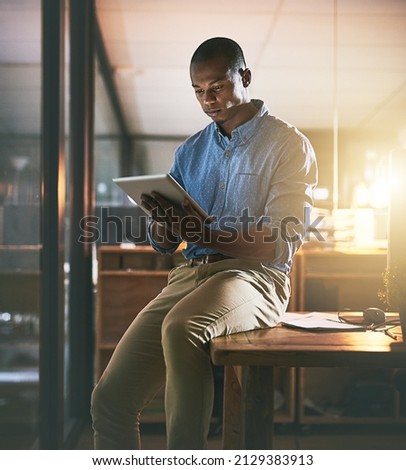 While others are dreaming hes making the dream work. Shot of a young businessman using a digital tablet during a late night in a modern office. Royalty-Free Stock Photo #2129383913