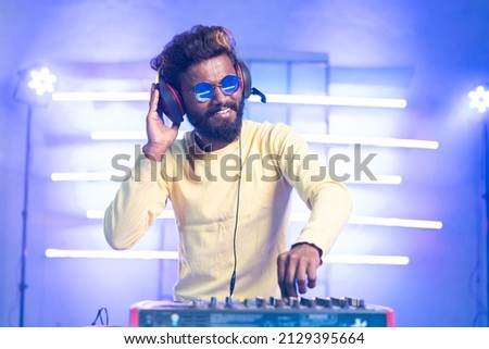 exicted dj sound device oprator with headphones by dancing at club - concept of entertainment, nightlife, music club and musician Royalty-Free Stock Photo #2129395664
