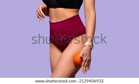 unrecognizable fit woman in top and high waist panties holding orange fruit. Faceless healthy slim female has sporty body without cellulite and orange peel. Healthy lifestyle. Beauty and health care Royalty-Free Stock Photo #2129406932