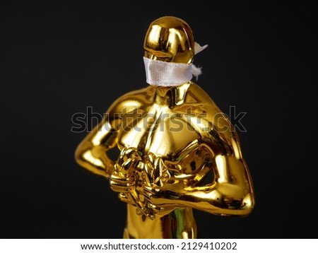 Hollywood Golden Oscar Academy award statue in medical mask on black background. Success and victory concept. Oscar ceremony in coronavirus covid-19 time