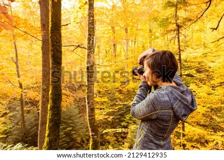 Woman trekking in the forest and taking pictures with dlsr camera