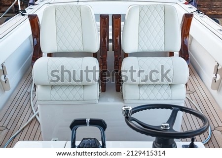 Luxury motorboat control cabin with white leather seats, steering wheel and gear lever. Royalty-Free Stock Photo #2129415314