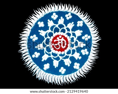 Rangoli design made by spreading colorful powder with om religious hinduism symbol at middle and isolated in black background.
