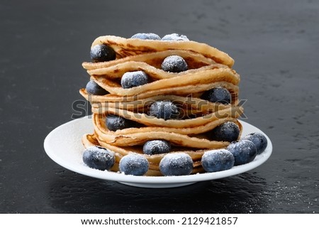 Stack of pancakes with blueberry and powdered sugar on white plate Close-up Selective focus