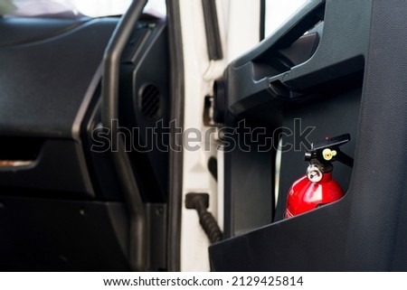Red fire extinguisher in a black truck door. Royalty-Free Stock Photo #2129425814