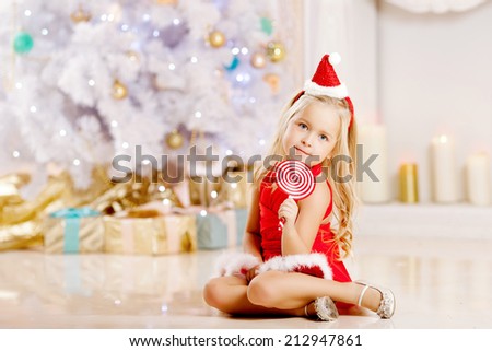 Beauty little Santa girl near the Christmas tree.  Happy girl  celebrates christmas.