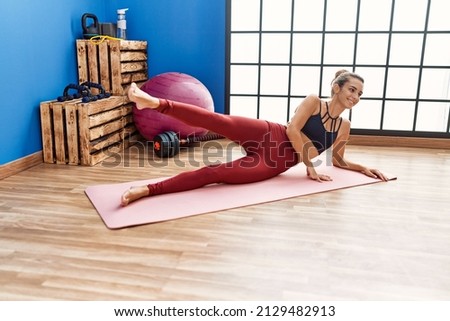 Young hispanic woman smiling confident stretching at sport center