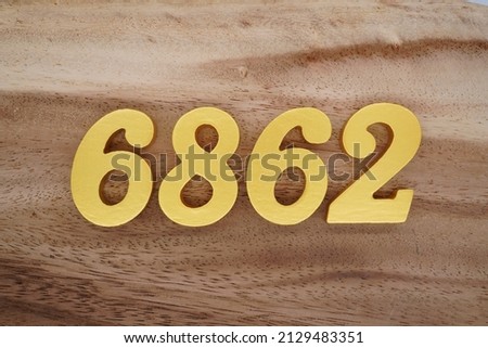 Wooden  numerals 6862 painted in gold on a dark brown and white patterned plank background.
