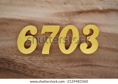 Wooden  numerals 6703 painted in gold on a dark brown and white patterned plank background.
