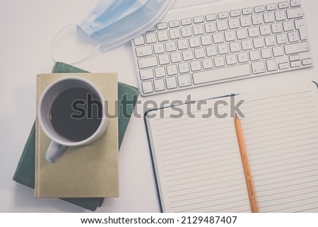 Desktop view with keyboard, pencil, agenda and books. Table with objects for smart working or homeschooling. Organization, remote work, study, creativity, production, indecision, confusion concept.