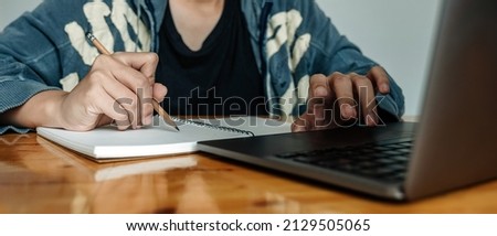 Cropped photo of woman writing making list taking notes in notepad working or learning on laptop indoors- educational course or training, seminar, education online concept