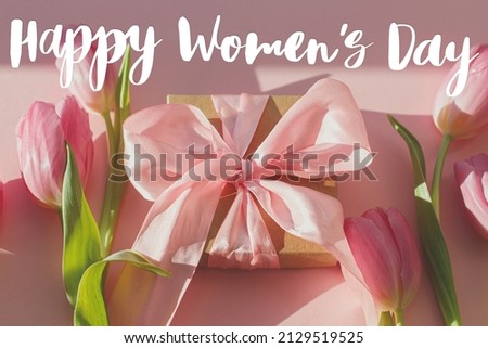 Happy womens day text on pink tulips and gift box in sunlight on pink background. Stylish greeting card. International Women's Day. 8 march. Handwritten lettering