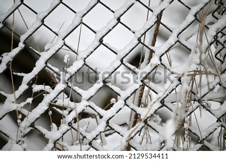 metal mesh fence with a layer of snow