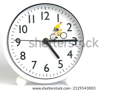 Miniature people toy figure photography. Cycling schedule concept. A biker cycling above clockwise, isolated on white background. Image photo